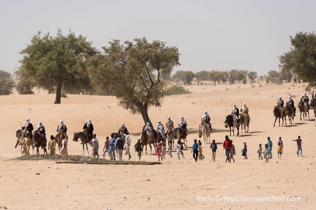 caballeros kanembou con turbantes y espadas en alto seguidos de un grupo de niños en chad
