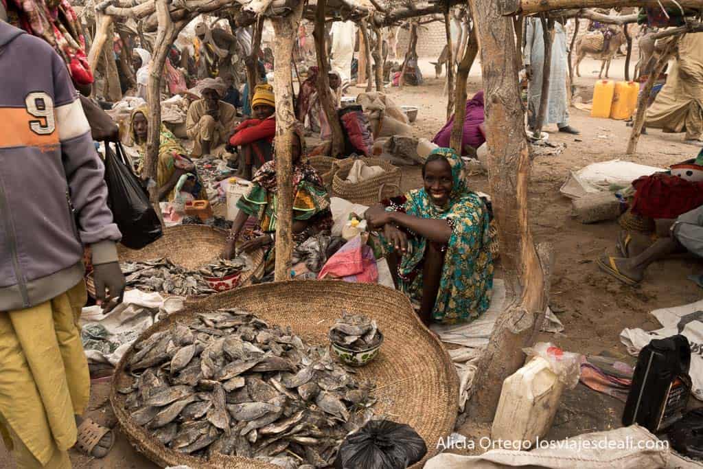 dried fish stall in Isseirom with smiling saleswoman squatting down. 