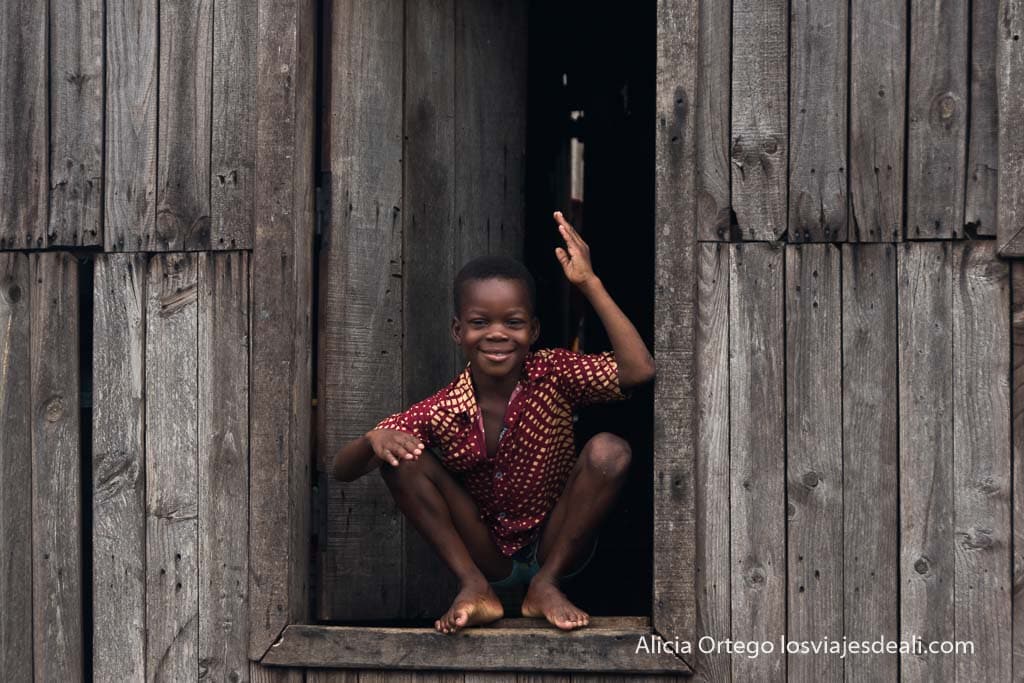 Niño de makoko en la puerta de su casa saludando
